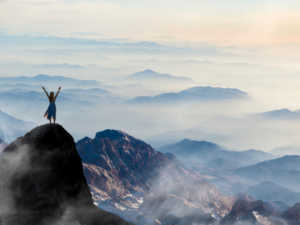 Mujer en la sima de una montaña alta - se siente feliz con su libertad financiera